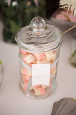 Bu büyüleyici görüntü, gerçek bir düğünün zarif dekorunu ve büyüleyici çiçek düzenlemelerini gözler önüne seriyor. Fotoğrafta zarif çiçekler, mumlar ve diğer dekoratif el ile süslenmiş büyüleyici bir düğün yerinde güzel dekore edilmiş bir masa yer alıyor.