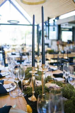 Bu büyüleyici görüntü, gerçek bir düğünün zarif dekorunu ve büyüleyici çiçek düzenlemelerini gözler önüne seriyor. Fotoğrafta zarif çiçekler, mumlar ve diğer dekoratif el ile süslenmiş büyüleyici bir düğün yerinde güzel dekore edilmiş bir masa yer alıyor.