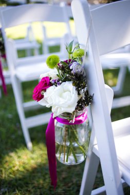 Bu büyüleyici görüntü, gerçek bir düğünün zarif dekorunu ve büyüleyici çiçek düzenlemelerini gözler önüne seriyor. Fotoğrafta zarif çiçekler, mumlar ve diğer dekoratif el ile süslenmiş büyüleyici bir düğün yerinde güzel dekore edilmiş bir masa yer alıyor.