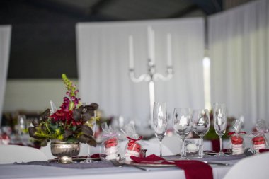 Bu büyüleyici görüntü, gerçek bir düğünün zarif dekorunu ve büyüleyici çiçek düzenlemelerini gözler önüne seriyor. Fotoğrafta zarif çiçekler, mumlar ve diğer dekoratif el ile süslenmiş büyüleyici bir düğün yerinde güzel dekore edilmiş bir masa yer alıyor.