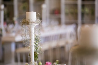 Bu büyüleyici görüntü, gerçek bir düğünün zarif dekorunu ve büyüleyici çiçek düzenlemelerini gözler önüne seriyor. Fotoğrafta zarif çiçekler, mumlar ve diğer dekoratif el ile süslenmiş büyüleyici bir düğün yerinde güzel dekore edilmiş bir masa yer alıyor.