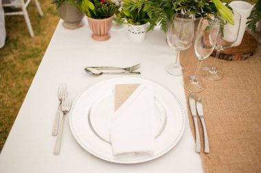 Bu büyüleyici görüntü, gerçek bir düğünün zarif dekorunu ve büyüleyici çiçek düzenlemelerini gözler önüne seriyor. Fotoğrafta zarif çiçekler, mumlar ve diğer dekoratif el ile süslenmiş büyüleyici bir düğün yerinde güzel dekore edilmiş bir masa yer alıyor.