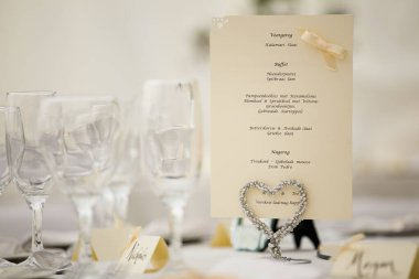 Bu büyüleyici görüntü, gerçek bir düğünün zarif dekorunu ve büyüleyici çiçek düzenlemelerini gözler önüne seriyor. Fotoğrafta zarif çiçekler, mumlar ve diğer dekoratif el ile süslenmiş büyüleyici bir düğün yerinde güzel dekore edilmiş bir masa yer alıyor.