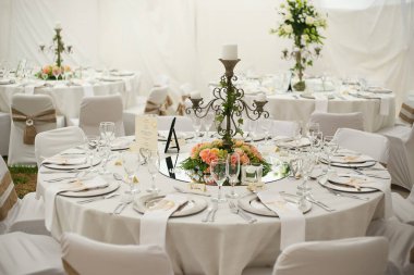 Bu büyüleyici görüntü, gerçek bir düğünün zarif dekorunu ve büyüleyici çiçek düzenlemelerini gözler önüne seriyor. Fotoğrafta zarif çiçekler, mumlar ve diğer dekoratif el ile süslenmiş büyüleyici bir düğün yerinde güzel dekore edilmiş bir masa yer alıyor.