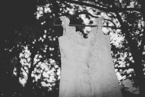 This captivating image showcases a wedding dress with intricate details photographed in creative and unique ways. The photograph features a stunning white wedding dress with intricate lace detailing and delicate beading. The dress is photographed fro