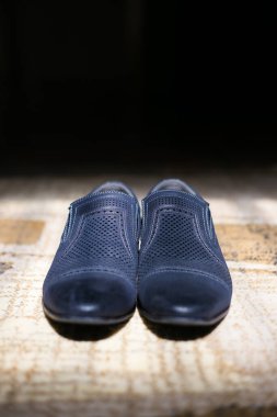 Bu büyüleyici görüntü, damadın büyük günü için giyinirken takım elbisesi, ayakkabıları ve kol düğmeleri de dahil olmak üzere düğün kıyafetini gösteriyor. Fotoğraf, damadın kıyafetinin karmaşık detaylarını vurguluyor. Güzel bir kompozisyon oluşturuyor. 