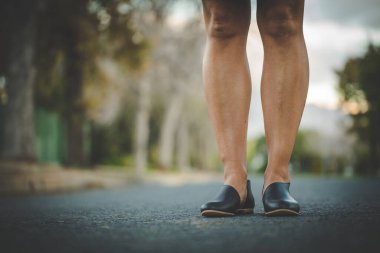 El yapımı deri ayakkabılar giyen kaslı bacaklı güzel bir kadın resmi..