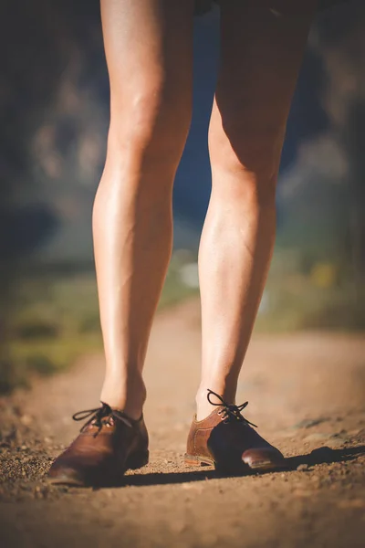 一个穿着手工皮鞋 肌肉发达的女人在土路上行走的特写镜头 — 图库照片