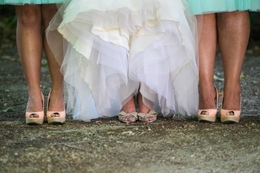 Bir gelin ve nedimeleri ayaklarını ve ayakkabılarını göstermek için elbiselerini kaldırıyorlar..