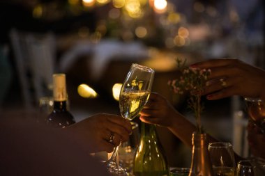 A group of people cheering with champagne glasses at a wedding. The focus is on the hands and glasses. The people are all smiling and looking happy. clipart