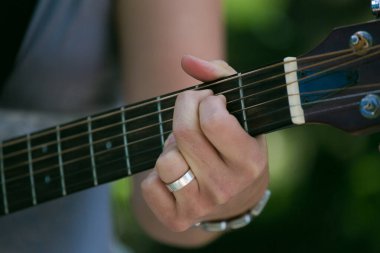 Bir fonksiyonda gitar çalan kişinin elleri ve enstrümanına odaklandığı yakın plan..