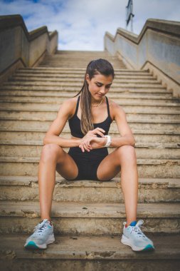 Young female athlete in black sportswear working out in an urban outdoor environment, showcasing strength and fitness. clipart