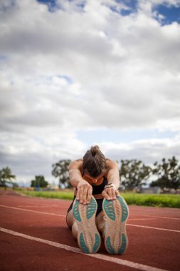 Female athlete in black sportswear training on a professional running track, performing dynamic exercises and showcasing endurance and athleticism. clipart