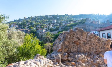 Eski liman duvarları ve Alanya, Türkiye 'deki Tersane Plaji plajı. Arka planda insanlar ve konut binaları var.