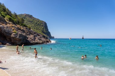 Alanya, Antalya - Türkiye 08: 11 2023: Alanya yarımadası, Antalya, Türkiye 'de deniz ve kayalarla kaplı Kleopatra Sahili. Yüksek yeşil uçurumu ve Alanya Kalesi olan güzel bir turizm manzarası..