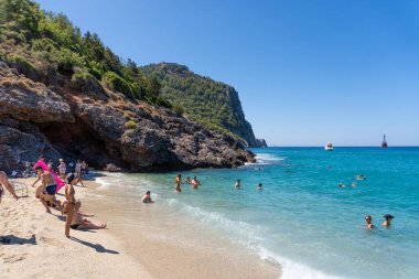 Alanya, Antalya - Türkiye 08: 11 2023: Alanya yarımadası, Antalya, Türkiye 'de deniz ve kayalarla kaplı Kleopatra Sahili. Yüksek yeşil uçurumu ve Alanya Kalesi olan güzel bir turizm manzarası..