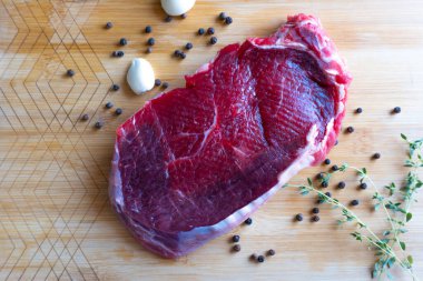 Tahta üzerinde taze çiğ biftek, sarımsaklı karabiber ve kekik.