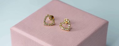 Kadın küpeleri altın. Pembe kutu vektöründe 14 kilo kalp şeklinde.