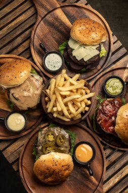 Restoran ahşap masasında bir sürü farklı gurme burger seçimi var.