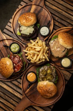 Restoran ahşap masasında bir sürü farklı gurme burger seçimi var.