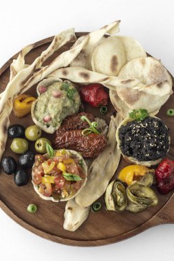Vejetaryen tapas atıştırmalıkları beyaz arka planda ahşap tabakları paylaşıyor