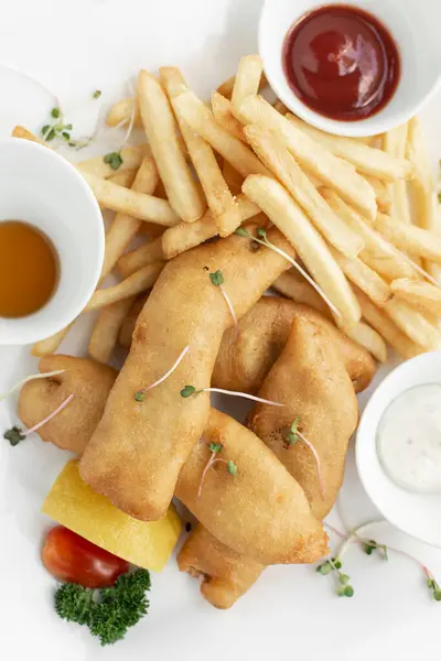 イギリスの伝統的な魚とチップの食事 ホワイトプレートと白い背景のレストランで ロイヤリティフリーのストック画像