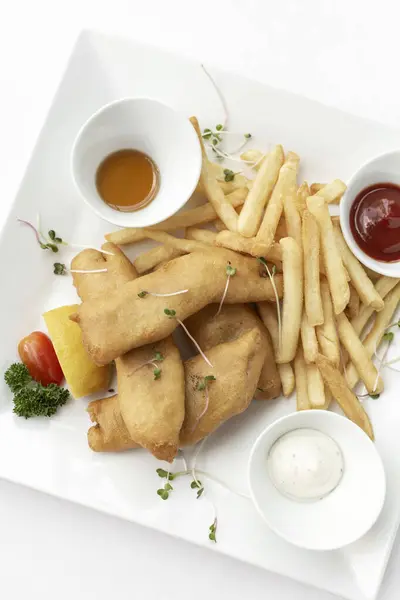 英国传统的炸鱼薯条在白盘和白底的餐馆里就餐 图库照片