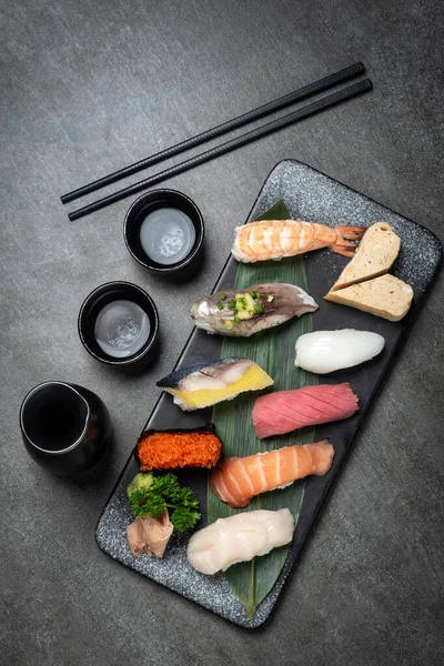 和食レストランのグレーの背景に日本酒をセットしたオマキスミックス寿司 ストック画像