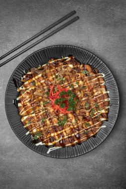 Meşhur Okonomiyaki geleneksel Japon baharatlı krepi restoranında gri arka planda.