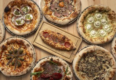 Restoran masasında geleneksel İtalyan ahşap pizza çeşitleri var.