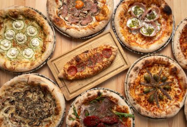 Restoran masasında geleneksel İtalyan ahşap pizza çeşitleri var.