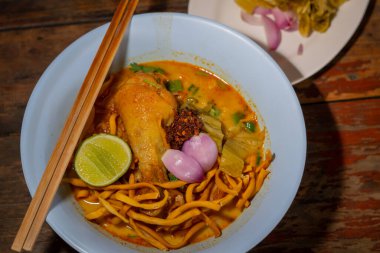 Khao Soi, Khao Soi Kai, Thai Noodles Khao Soi, ahşap zeminde baharatlı körili tavuk, Kuzey Tayland yemeği konsepti. (Lanna yemeği)