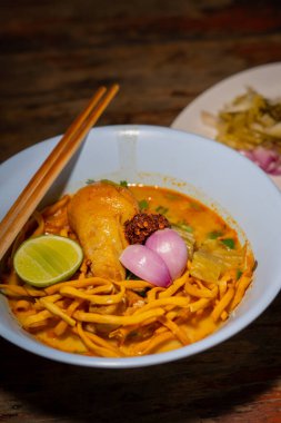 Khao Soi, Khao Soi Kai, Thai Noodles Khao Soi, ahşap zeminde baharatlı körili tavuk, Kuzey Tayland yemeği konsepti. (Lanna yemeği)