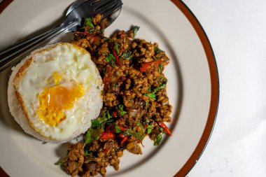 Stir fried Thai basil with minced pork and a fried egg on white plate