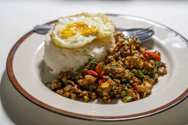 Stir fried Thai basil with minced pork and a fried egg on white plate