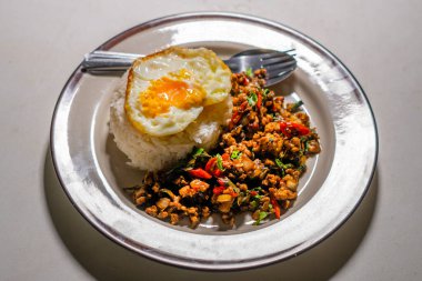 Stir fried Thai basil with minced pork and a fried egg on white plate