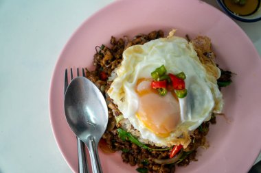 Stir fried Thai basil with minced pork and a fried egg on white plate