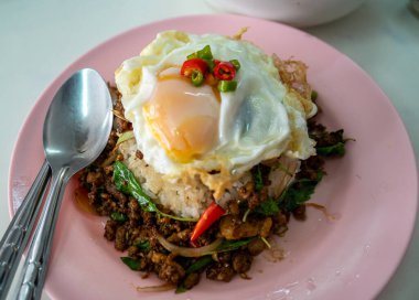 Stir fried Thai basil with minced pork and a fried egg on white plate