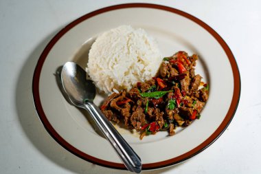 Stir fried Thai basil with minced pork and a fried egg on white plate