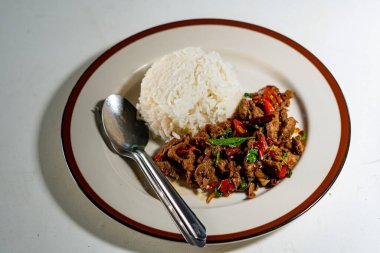 Stir fried Thai basil with minced pork and a fried egg on white plate