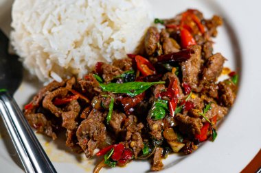 Stir fried Thai basil with minced pork and a fried egg on white plate