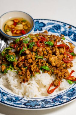 Stir fried Thai basil with minced pork and a fried egg on white plate