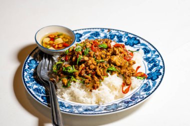 Stir fried Thai basil with minced pork and a fried egg on white plate