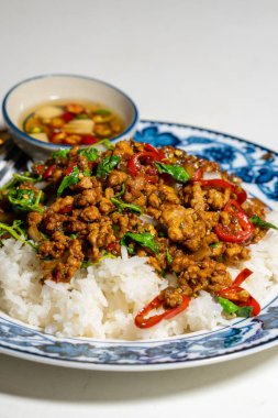 Stir fried Thai basil with minced pork and a fried egg on white plate