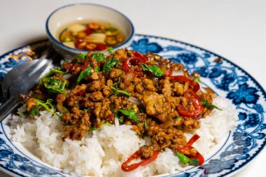 Stir fried Thai basil with minced pork and a fried egg on white plate