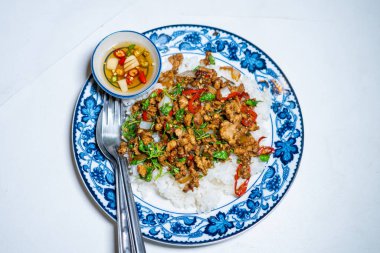 Stir fried Thai basil with minced pork and a fried egg on white plate