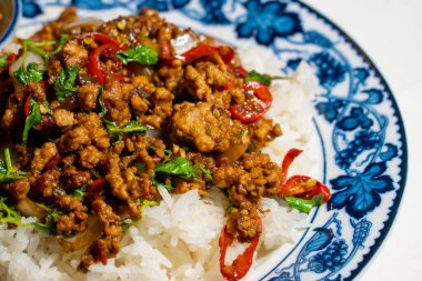 Stir fried Thai basil with minced pork and a fried egg on white plate