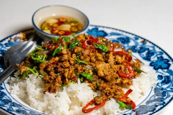 Stir fried Thai basil with minced pork and a fried egg on white plate