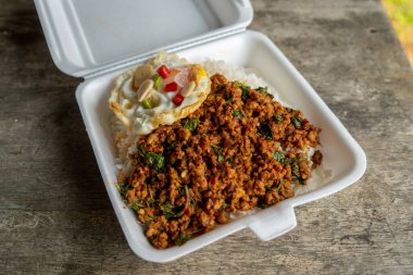 Stir fried Thai basil with minced pork and a fried egg on white plate
