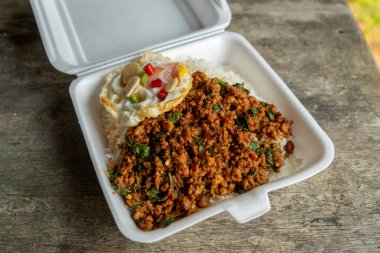 Stir fried Thai basil with minced pork and a fried egg on white plate